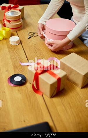 Mani di donna irriconoscibile che avvolgono con nastro un regalo rosa,  scatola regalo, natale o altro regalo fatto a mano di festa, facendo arco  al momento scatola, d Foto stock - Alamy