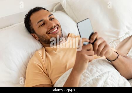 Sopra Vista dell'uomo Arabo che usa il testo del telefono in camera da letto Foto Stock