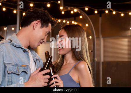 felice asiatico adolescente coppia uomo e donna in amore bere birra alcol e tostatura bottiglia in festa. giovane coppia felice amore e romantico Foto Stock