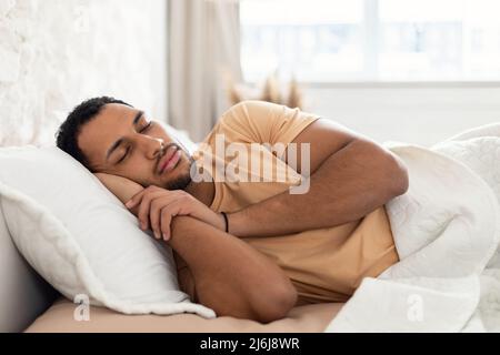 Dormendo maschio arabo giace in letto in camera da letto a casa Foto Stock