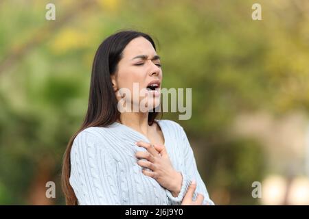 Donna stressata che ha problemi di respiro camminando in un parco Foto Stock