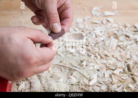 Cucchiaio di legno autointagliato bloccato in morsa lavorato con carta vetrata su un banco da lavoro con trucioli di legno, Germania Foto Stock
