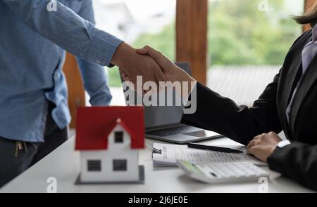 Agenti immobiliari e clienti scuotono le mani per congratularsi con la firma di un contratto per acquistare una casa con terra e assicurazione, handshake e buona risposta Foto Stock