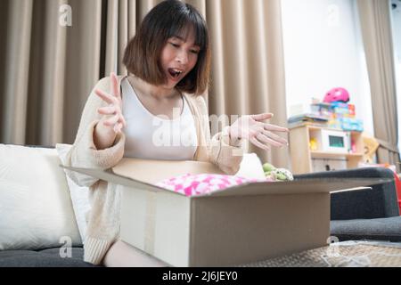 Concetto di consegna, posta e gente - donna sorridente che apre la scatola di cartone a casa. Foto Stock