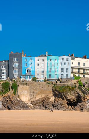 Tenby South Beach, vista in estate delle persone che camminano sotto la proprietà colorata su scogliere che si affacciano South Beach a Tenby, Pembrokeshire, Galles Foto Stock