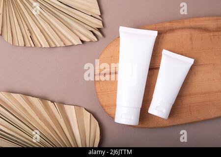 Vista dall'alto di due tubi cosmetici bianchi su podium.Earth tones in legno, concetto ecologico. Foto Stock