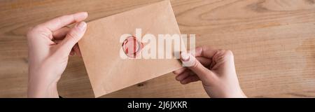 vista dall'alto della busta di carta del mestiere con il bollo di cera nelle mani del notaio tagliato, il banner Foto Stock