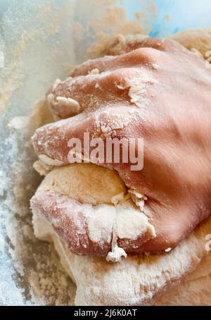 Donna impastare a mano l'impasto in una ciotola cosparsa di farina Foto Stock