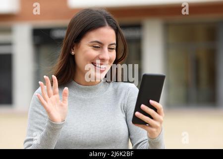 Buon saluto teen durante una videocall a piedi per strada Foto Stock