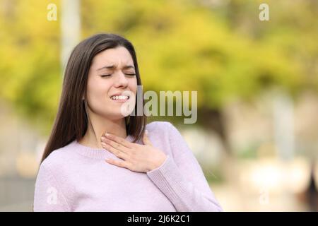 Teen che soffre mal di gola camminare in un parco Foto Stock