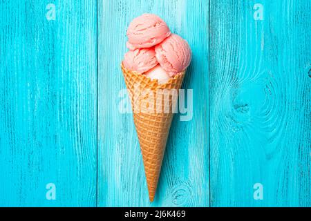 Gelato al lampone in un cono di waffle su sfondo blu. Foto Stock