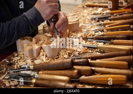 Maestro del legno al lavoro. Trucioli di legno, sgorbie e scalpelli sul banco di lavoro. Foto Stock