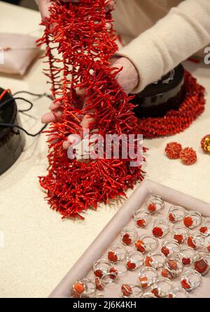 Collana di corallo rosso e anelli d'argento, sul tavolo del gioielliere. Foto Stock