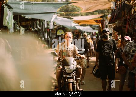 Anjuna, Goa, India - 19 febbraio 2020: Old Man Riding su moto scooter nel mercato Anjuna Foto Stock