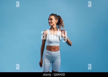 Giovane donna con corpo sottile e sano in piedi contro una parete blu Foto Stock
