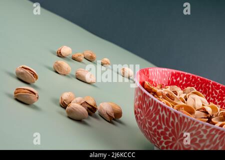 Gustosi pistacchi organici in una ciotola rossa sulla parte superiore di un tavolo verde, con spazio copia. Foto Stock