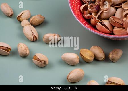 Gustosi pistacchi organici in una ciotola rossa sulla parte superiore di un tavolo verde, con spazio copia. Foto Stock
