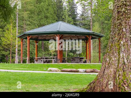 Pergola in legno nel parco con tavoli da giardino in legno e panchine all'ombra nella calda giornata di primavera. Foto di viaggio, messa a fuoco selettiva, nessuno Foto Stock