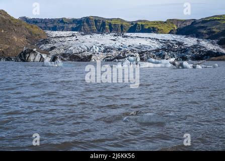 Ghiacciaio Solheimajokull nell'Islanda meridionale. La lingua di questo ghiacciaio scivola dal vulcano Katla. Splendida laguna glaciale lago con blocchi di ghiaccio un Foto Stock