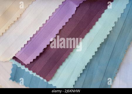 Campioni di strisce colorate con sfondo satinato. Bel tessuto di alta qualità per cucire biancheria da letto. Tessuti di cotone di colore bianco, verde, bordeaux vista dall'alto Foto Stock