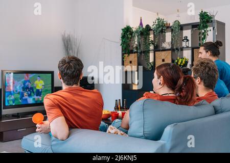 gruppo di amici che si rilassano sul divano a casa guardando una partita di calcio, trasmesso in televisione. Foto Stock