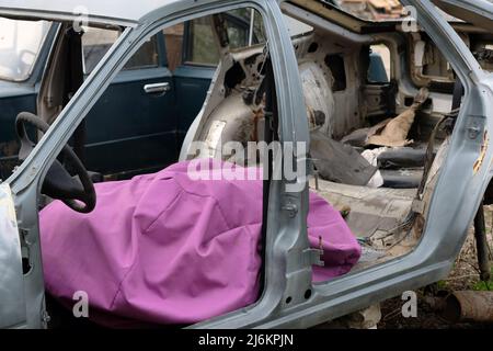 Corpo vuoto di una vecchia auto smontata con una borsa rosa. Volante, borsa in tessuto all'interno di una vecchia auto. Carrozzeria della vettura senza vento Foto Stock