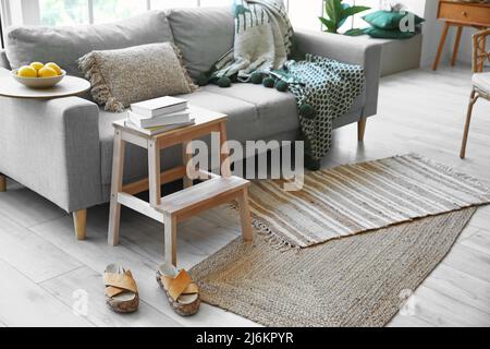 Scala a gradini in legno con divano, libri e scarpe femminili all'interno del soggiorno Foto Stock