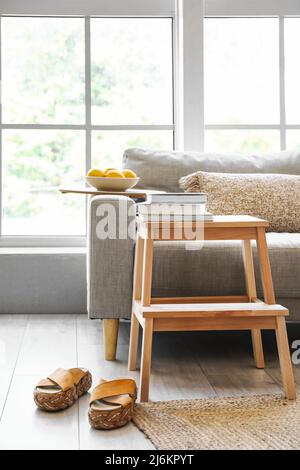 Scala a gradini in legno con divano, libri e scarpe femminili all'interno del soggiorno Foto Stock