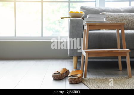 Scala a gradini in legno con divano, libri e scarpe femminili all'interno del soggiorno Foto Stock
