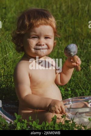 Il bambino piccolo carino sta alimentando usando il cucchiaio. Infanzia spensierata nel villaggio. Foto Stock