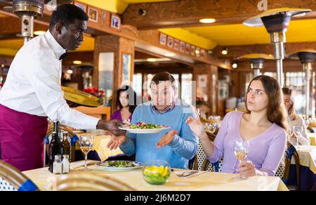 Ospiti dispiacenti in conflitto con il cameriere Foto Stock