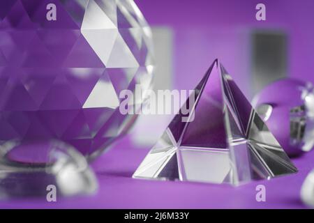 Luce rifrangente a prisma di cristallo, cristalli magici e piramide, sfera e cubo su sfondo viola. Pratica di cristallo di guarigione spirituale. Feng Shui, bravo Foto Stock