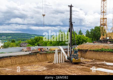 guidare un palo e formare un cumulo di pile durante la costruzione di una struttura con una fondazione di palo, fuoco selettivo Foto Stock