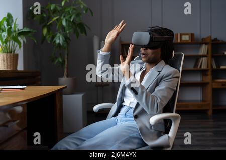 Giovane donna sorprende che testa gli occhiali VR alla prima volta mentre si siede in ufficio Foto Stock