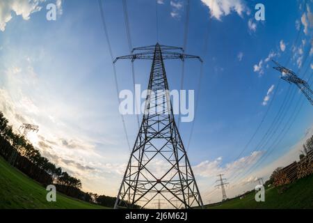 Pali metallici di trasmissione dell'elettricità su uno sfondo di cielo blu. Obiettivo fisheye. Foto Stock