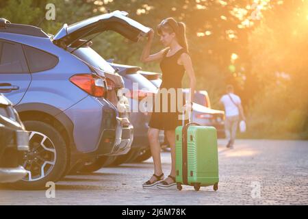 Giovane conducente donna che carica la valigia all'interno della sua auto. Concetto di viaggio e vacanza Foto Stock