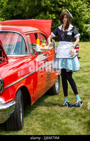 Un manichino ritrae un carhop in un ristorante drive-in con una berlina rossa Chevrolet 1957 durante una mostra di auto a Fort Wayne, Indiana, USA. Foto Stock