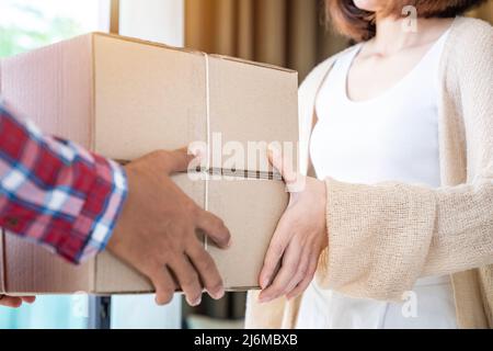 Addetto alla consegna che invia pacchi al cliente, Una persona che indossa una maglietta rossa sta consegnando pacchi ad un cliente soddisfatto. Lavoratore amichevole, di alta qualità Foto Stock