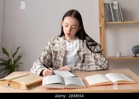 Studentessa asiatica studentessa studentessa a distanza da casa prendendo appunti. Distanza di apprendimento degli studenti adolescenti con i libri che fanno i compiti. Foto Stock