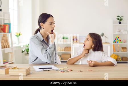 Bambino e terapista del discorso che fa gli esercizi per affrontare determinati problemi di pronuncia Foto Stock