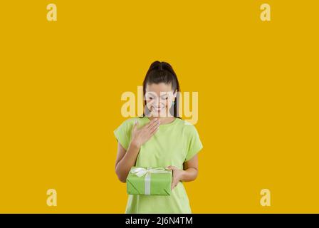 Felice giovane donna che ha ricevuto un regalo a sorpresa sta guardando la scatola e sorridendo Foto Stock