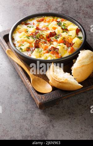 Zuppa polacca di patate con pancetta tradizionale Kartoflanka closeup nel recipiente sul vassoio di legno verticale Foto Stock