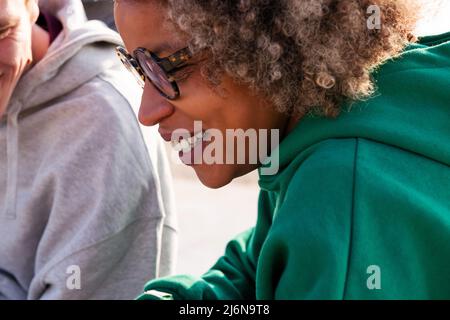 primo piano ritratto di una giovane donna latina sorridente accanto ad un amico irriconoscibile, concetto di stile di vita e amicizia Foto Stock