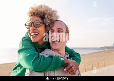 felice giovane coppia di donna latina e uomo caucasico abbraccio e ridere, concetto di amicizia e divertimento in un rapporto, spazio di copia per il testo Foto Stock