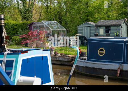 Le barche a remi ormeggiavano accanto ad un giardino ben tenuto appartenente ad un ormeggio residenziale sul canale Shropshire Union a Norbury, Staffordshire Foto Stock