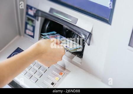 Primo piano della mano di una donna che preleva contanti, banconote in euro dal bancomat. Concetto di cliente finanziario e servizio bancario Foto Stock