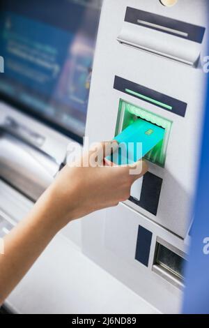 Primo piano di una mano di una giovane donna inserendo una carta di credito in un bancomat per trasferire denaro o prelevare. Clienti finanziari e servizi bancari Foto Stock