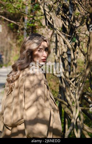 bella donna bionda che guarda indietro nel parco vicino fiori di ciliegia primo piano ritratto Foto Stock