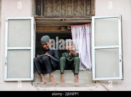 I ragazzi musulmani hanno visto usare i telefoni cellulari mentre si siedono sul balcone della loro casa dopo aver eseguito le preghiere di Eid al-Fitr che segnano la fine del mese santo di digiuno del Ramadan alla Brihanmumbai Municipal Corporation (BMC) Ground, Mumbai. EID-al-Fitr è celebrato da musulmani in tutto il mondo che segnano la fine del mese di digiuno dall'alba al tramonto durante il mese santo del Ramadan. Foto Stock