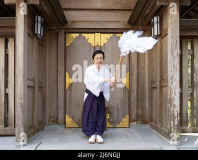 Il sacerdote Eishu Sato si dirige al Amanoiwato Jinja, il sacerdote ondeggia un harai-gushi, una bacchetta di legno con carta piegata, Shinto Shrine, Takachiho, Kyushu, Giappone Foto Stock